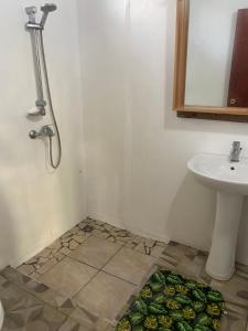 une salle de bain avec un lavabo, une douche et un tapis dans l'établissement Punahere lodge Ohotu, à Rangiroa