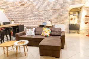 ein Wohnzimmer mit einer Couch und einer Ziegelwand in der Unterkunft Le Rinaldi Loft in Albi