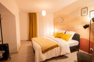 ein Hotelzimmer mit einem Bett mit gelben Kissen in der Unterkunft Le Rinaldi Loft in Albi