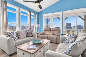 een woonkamer met blauwe muren en ramen bij Sunsets and the Sea in Thomas Landing