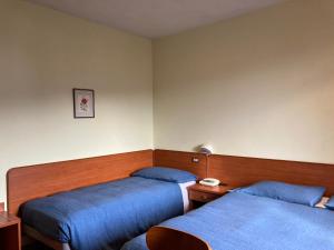 2 Betten in einem Zimmer mit blauer Bettwäsche in der Unterkunft B B Regina in Abetone