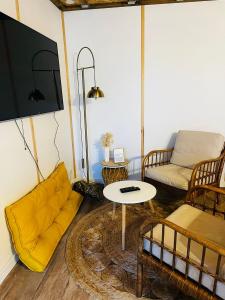 a living room with a yellow couch and a tv at Le chalet à bulles in Sainte-Marie-au-Bosc