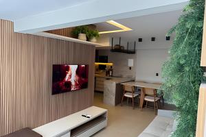 uma cozinha e sala de jantar com uma televisão na parede em Mont Blanc Apartamentos em Vinhais