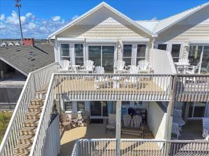 a house with a deck with white chairs and tables at Drift Away in Topsail Beach