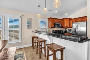 a kitchen with wooden cabinets and a bar with stools at Drift Away in Topsail Beach