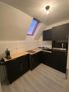eine Küche im Dachgeschoss mit schwarzen Schränken und einem Fenster in der Unterkunft Wuppertal am Toelleturm in Wuppertal + 9 Fotos