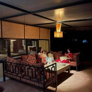 two people sitting on a couch in a living room at Unique Sahara Camp in Merzouga