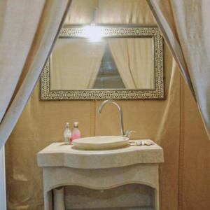 a bathroom with a sink and a mirror at Unique Sahara Camp in Merzouga +35 photos