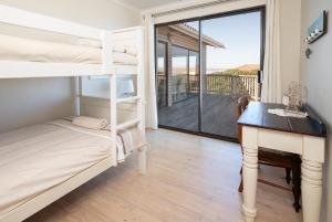 a bedroom with bunk beds and a desk and a balcony at Leef op Hoop in Boggomsbaai