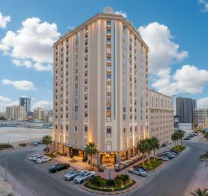 a large white building with cars parked in a parking lot at Ramee Rose Hotel in Manama