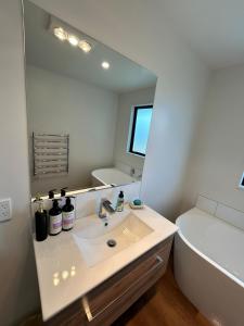 een badkamer met een wastafel, een spiegel en een bad bij Stackwood Lodge - Relaxed stay for all seasons in Woodend +45 foto's