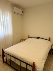um pequeno quarto com uma cama com lençóis brancos em חלון לצפון em Qiryat Shemona