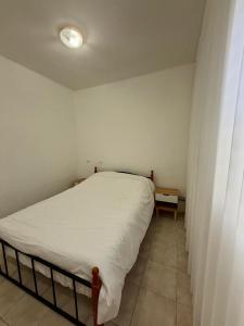 um pequeno quarto com uma cama com um lençol branco em חלון לצפון em Qiryat Shemona mais 4 fotografias