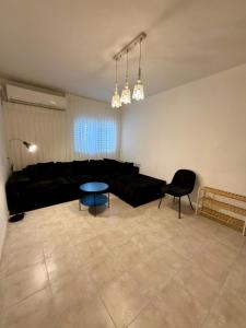 uma sala de estar com um sofá preto e uma mesa em חלון לצפון em Qiryat Shemona
