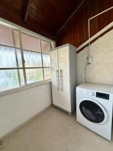 a laundry room with a washing machine and window at בית למטייל קריית שמונה in Qiryat Shemona