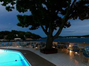 a swimming pool with a tree and tables and chairs at Baypoint Condo, Pool, Dock, relaxing location in Lake Ozark