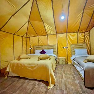 a bedroom with two beds in a tent at Unique Sahara Camp in Merzouga +35 photos
