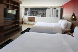 ein Hotelzimmer mit zwei Betten und einem Flachbildfernseher in der Unterkunft The Place Hotel in Quito + 25 Fotos