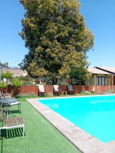a swimming pool with a table and chairs and a tree at Las Cabañas del Francés in Vallenar