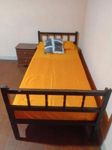 ein Bett mit gelben Laken und einem Holzrahmen in der Unterkunft La Esperanza in Puerto Esperanza