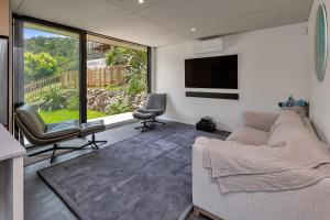 uma sala de estar com um sofá e uma TV de tela plana em The Pods - Tutukaka Coast Holiday Home em Ngunguru