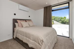 um quarto com uma cama e uma janela grande em The Pods - Tutukaka Coast Holiday Home em Ngunguru