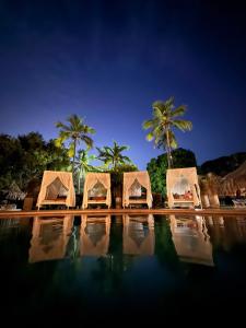 a group of tents sitting next to a pool with palm trees at Hotel y Spa Santa Fe Colonial in Santa Fe de Antioquia