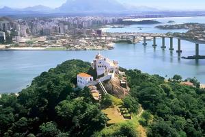 eine Burg auf einer Insel im Wasser mit einer Brücke in der Unterkunft PRAIA DE ITAPARICA BEACH 24HRS in Vila Velha + 39 Fotos