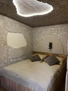 Leśna Grota na Roztoczu في Górecko Stare: سرير في غرفة بجدار حجري