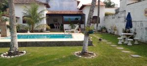 a house with a swimming pool and two palm trees at SUITE ACONCHEGANTE 02 in Saquarema +2 photos