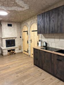 Leśna Grota na Roztoczu في Górecko Stare: مطبخ مع دواليب خشبية ومدفأة