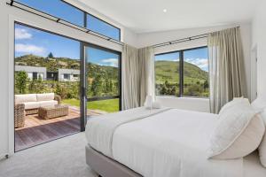 a bedroom with a large bed and large windows at Te Maunga Retreat | Views, Space & Near Ski Fields in Frankton