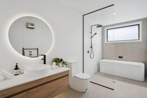 a bathroom with a toilet and a sink and a mirror at Te Maunga Retreat | Views, Space & Near Ski Fields in Frankton +16 photos