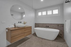 a bathroom with a tub and a sink and a mirror at Goonawarra Getaway at Mooloolaba in Mooloolaba