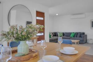 a table with a vase of flowers and wine glasses at Goonawarra Getaway at Mooloolaba in Mooloolaba