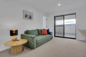 a living room with a green couch and a table at Goonawarra Getaway at Mooloolaba in Mooloolaba