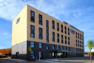 Un gran edificio con un cartel al costado. en Holiday Inn Express & Suites Barcelona - Sabadell by IHG, en Sabadell