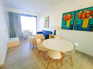 Una sala de estar con una mesa y sillas blancas. en Departamento cerca del mar en Puerto Aventuras #105, en Puerto Aventuras 9 fotos más