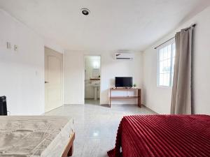ein weißes Zimmer mit zwei Betten und einem Fernseher in der Unterkunft Monet Hotel Motul in Motul de Felipe Carrillo Puerto