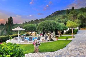 un gruppo di sedie e un ombrellone in giardino di Villa Claire 10-Acre Private Estate with Pool near Corfu Old Town a Gastouri