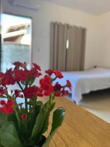 a vase with red flowers sitting on a table at Studio Park e Mar a 600m do Beto Carrero in Penha
