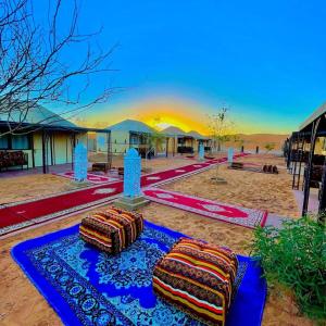 two pillows sitting on a blue rug in the desert at Unique Sahara Camp in Merzouga