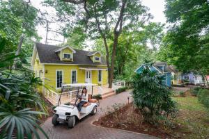 a woman riding a golf cart in front of a yellow house at Puprai Tarnnarm Resort in Thong Pha Phum +109 photos