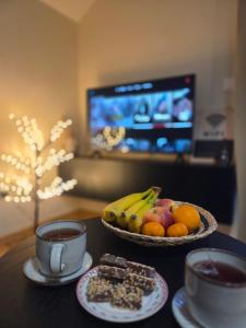 a table with a bowl of fruit and a cup of coffee at Tara Breeze Apartments in Kolašin