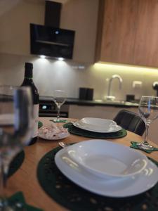 a table with a white plate and two wine glasses at Tara Breeze Apartments in Kolašin