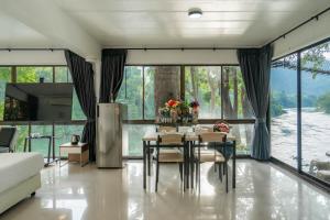 Puprai Tarnnarm Resort في ثونغ فا فوم: غرفة طعام بها طاولة وكراسي ونوافذ