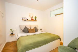 een slaapkamer met een bed met een groene deken bij Fidelios Altstadt Appartements in Weiden