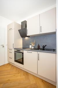 een witte keuken met witte kasten en een spoelbak bij Fidelios Altstadt Appartements in Weiden
