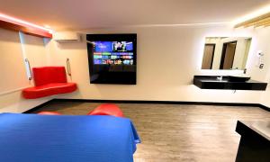 Una habitación con una mesa azul y sillas rojas y un televisor. en Autoparador Del Valle, en Ciudad de México