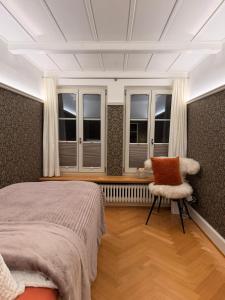 Un dormitorio con una cama y una silla y ventanas. en Little Escape House with Sauna & perfect Location, en Thun 17 fotos más